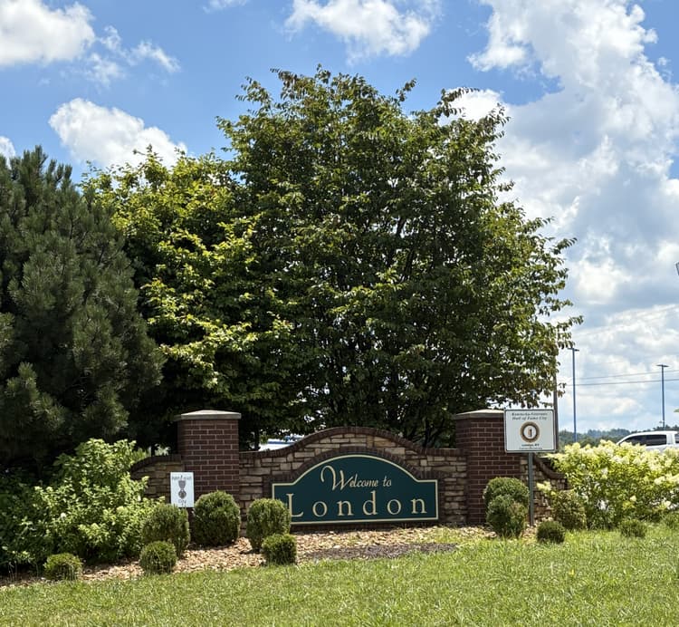 Brick "Welcome to London" sign surrounded by trees and shrubs